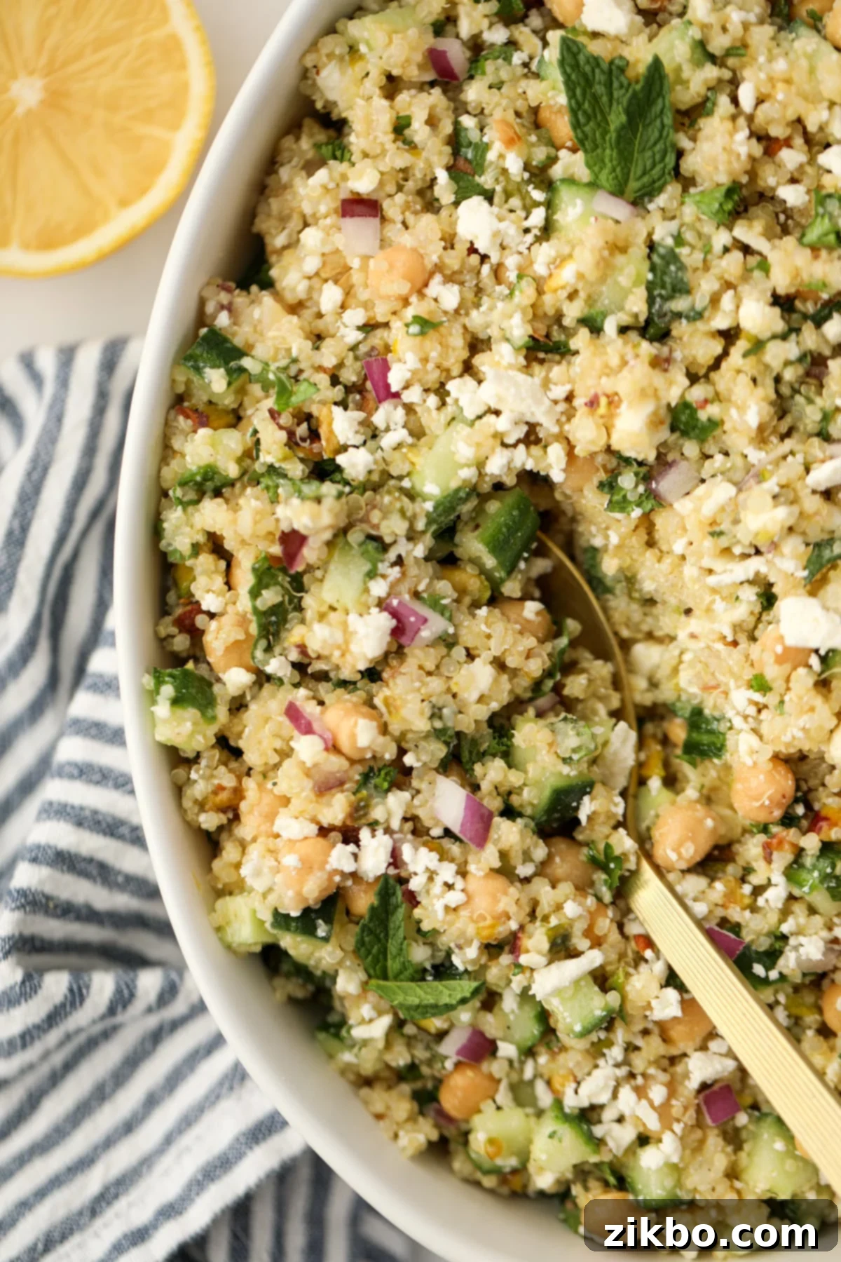 Scooping feta and quinoa salad from a bowl, highlighting the cheesy texture and fresh ingredients.