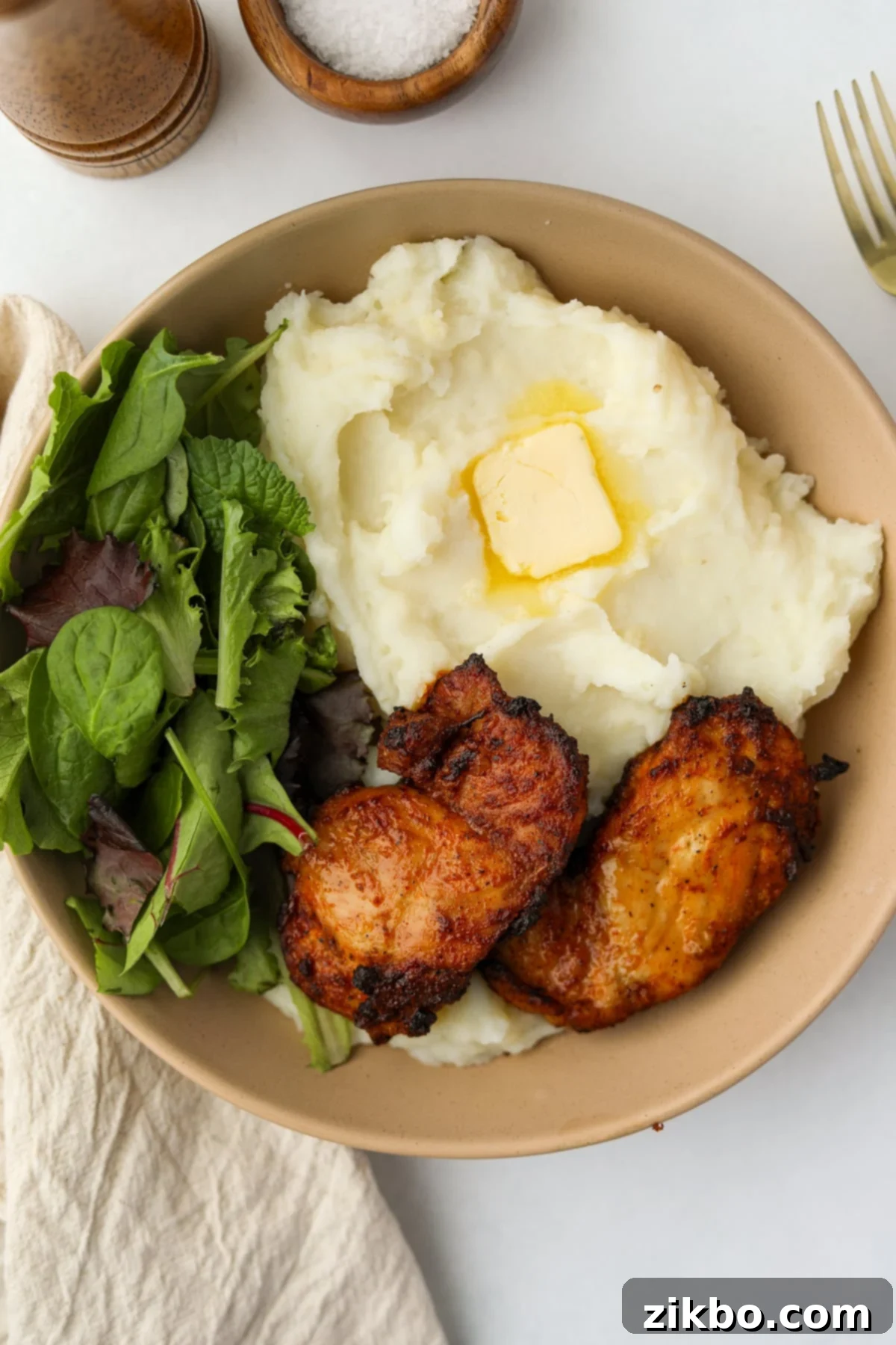 Crispy and Juicy Air Fryer Chicken Thighs 2 A bowl featuring mashed potatoes, salad, and some crispy chicken thighs.