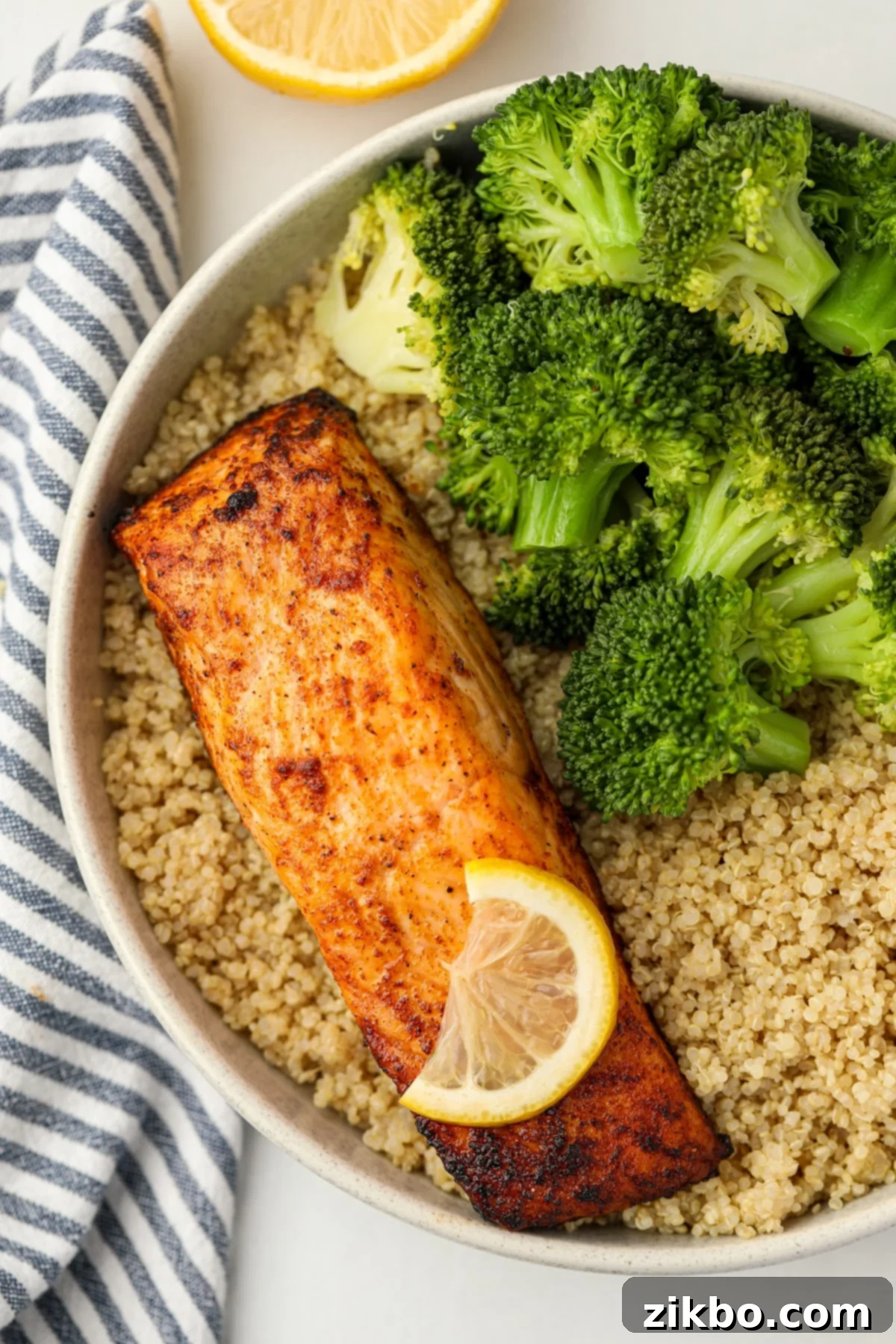 A perfectly cooked salmon fillet on a bed of fluffy cooked quinoa, served with a vibrant side of steamed broccoli.