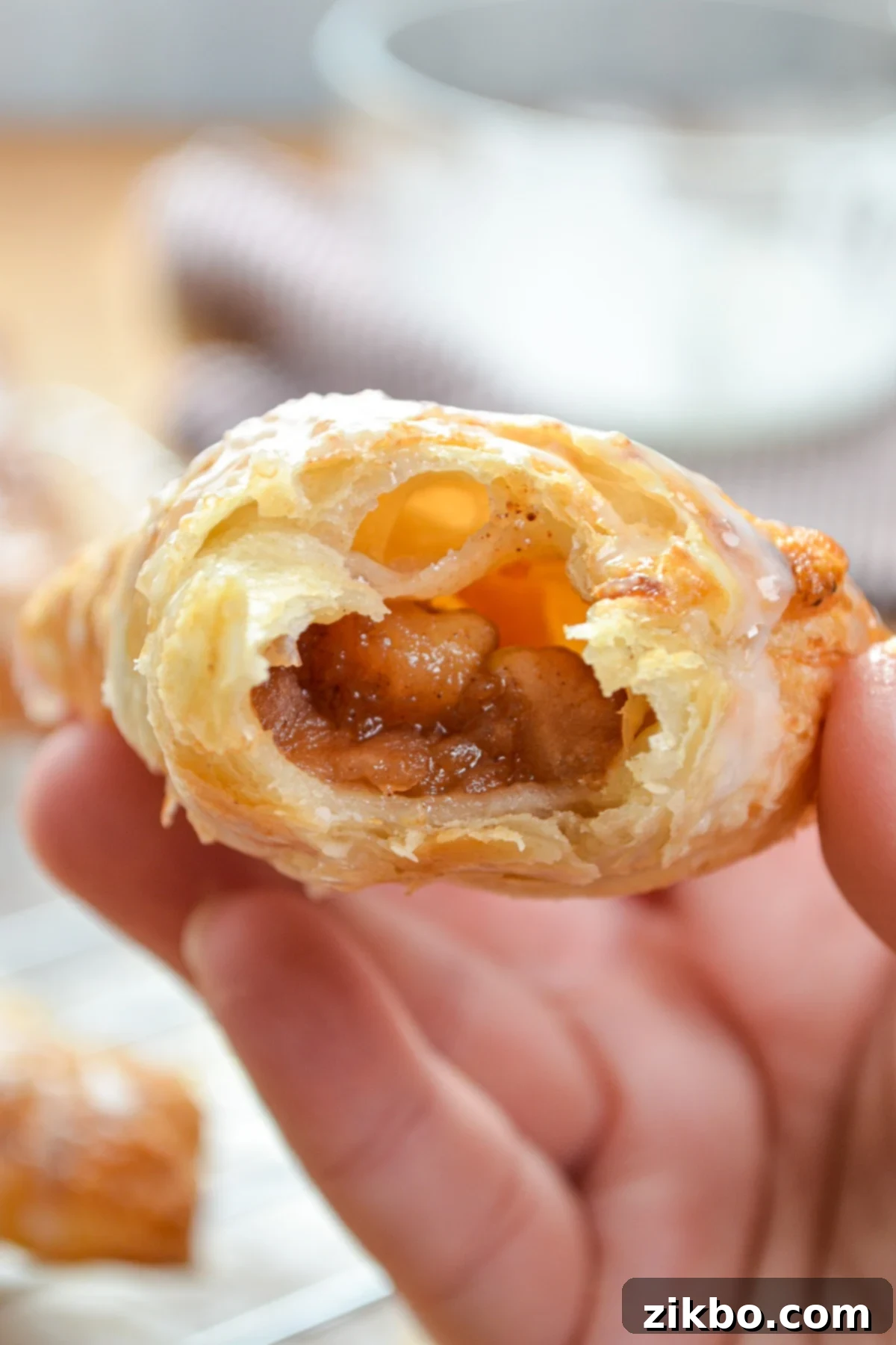An apple turnover, with a bite taken out of it, exposing the delicious apple filling.