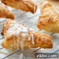 An apple turnover, being drizzled with a simple glaze.
