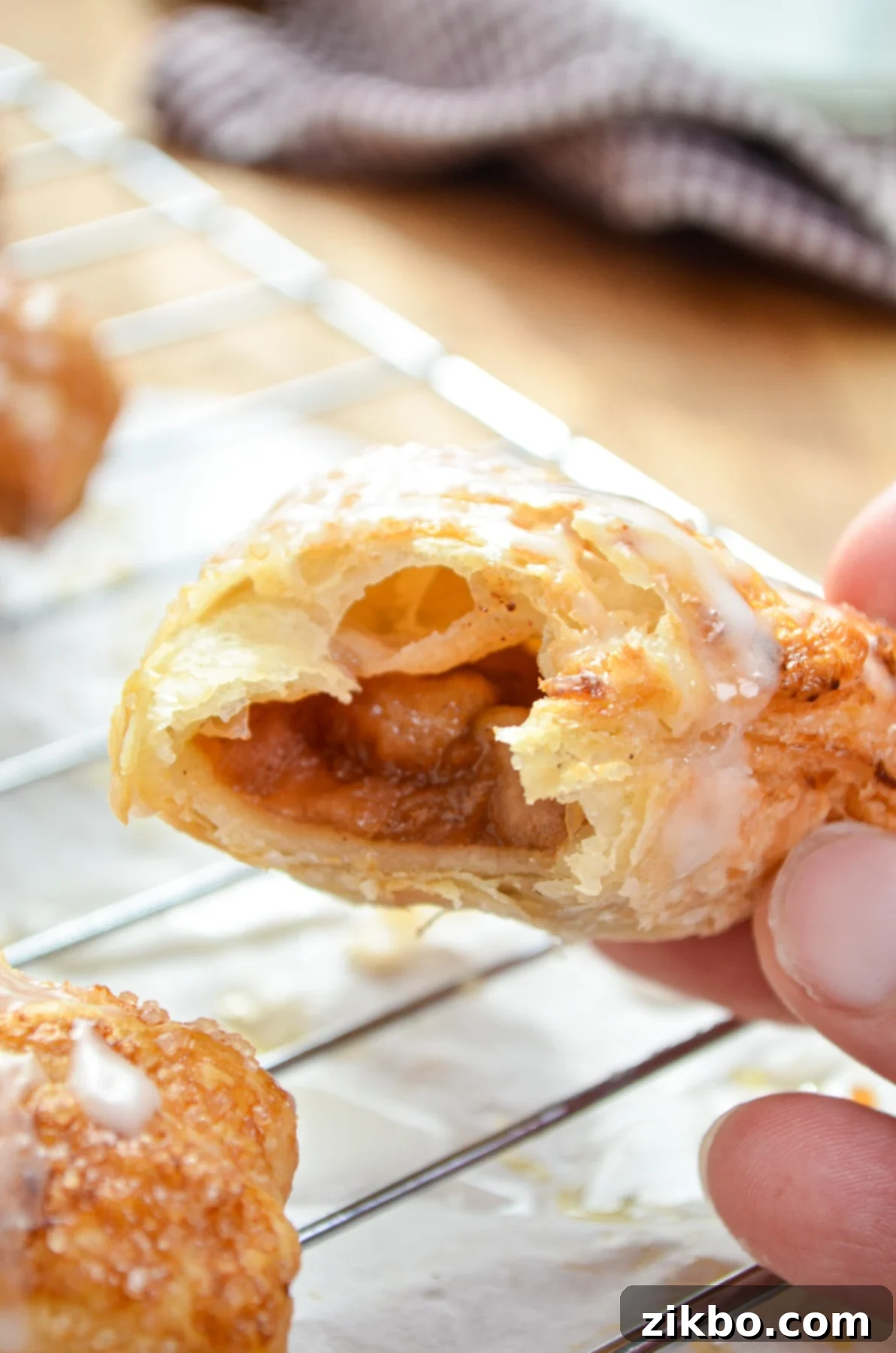 An air-fried apple turnover, with a delicious bite taken out, resting on a wire cooling rack.