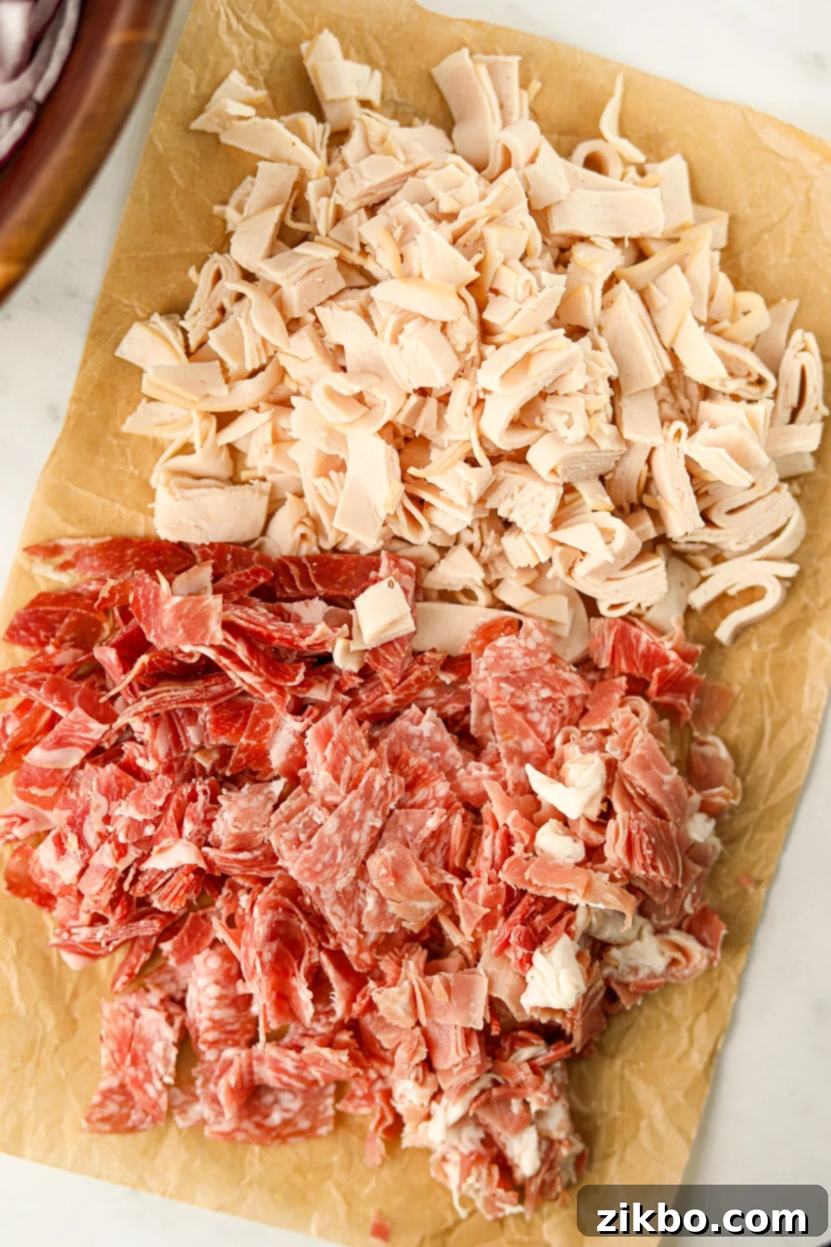 A pile of chopped deli meat on a sheet of parchment paper.