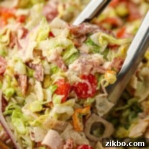 A pair of tongs picking up a portion of chopped Italian salad.