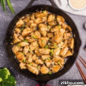 A skillet filled with cooked chicken stir fry with a golden sauce.