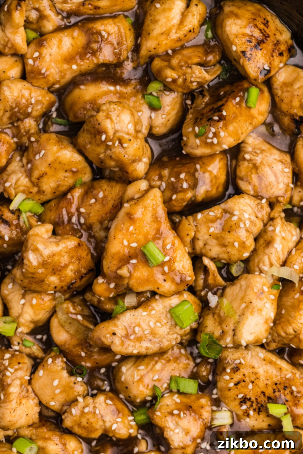 A close up on cubed cooked chicken that's been cooked in a golden sauce.
