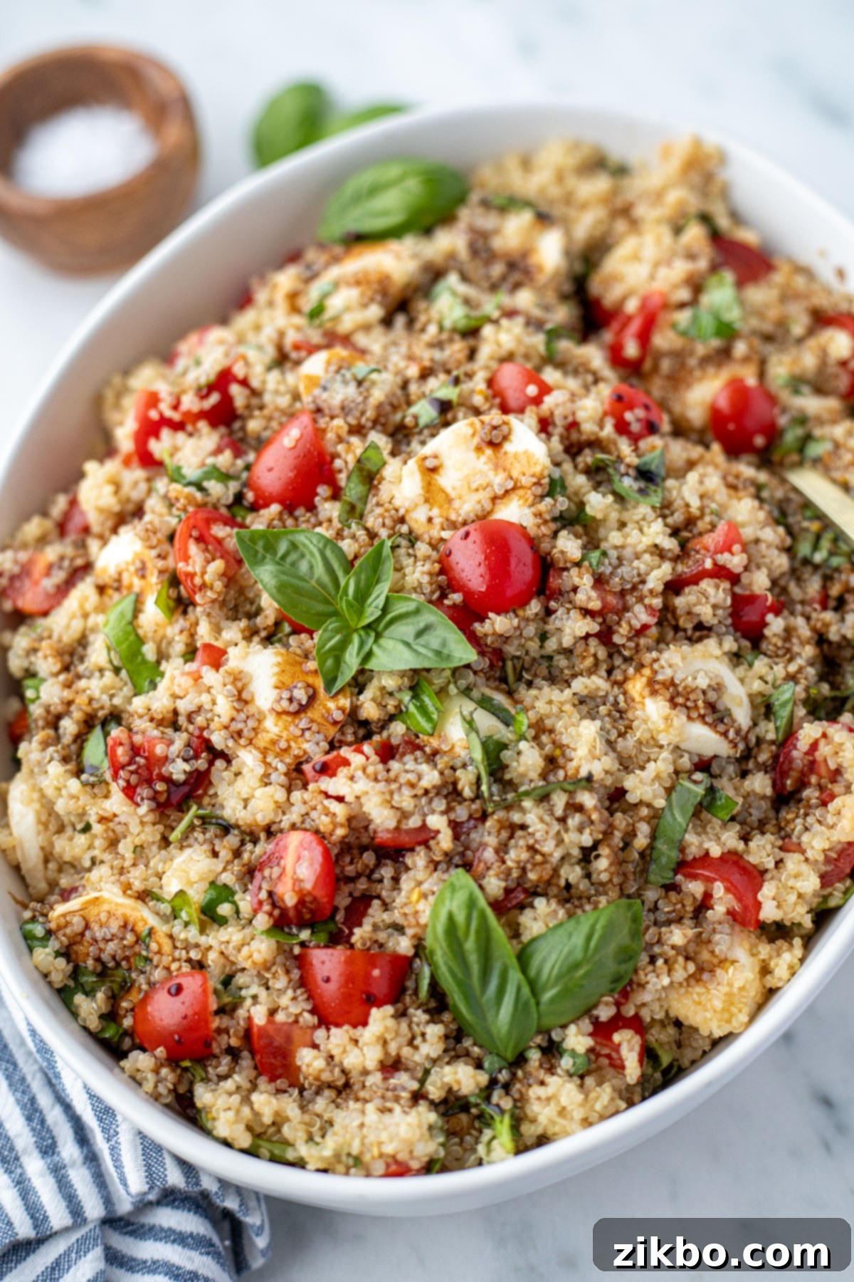 Fresh Caprese Quinoa 6 A large bowl of quinoa salad topped with fresh basil and tomatoes.