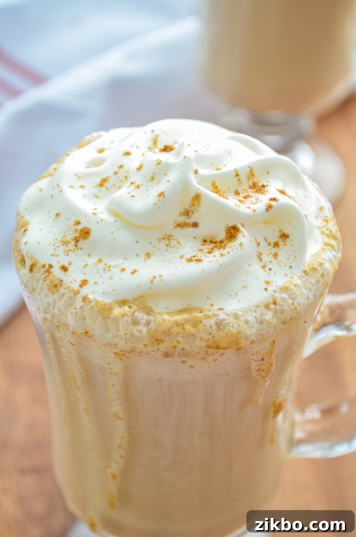 A beautifully presented glass mug of homemade Instant Pot Pumpkin Spice Latte, topped with fluffy whipped cream and a sprinkle of pumpkin spice, ready for a delightful sip.
