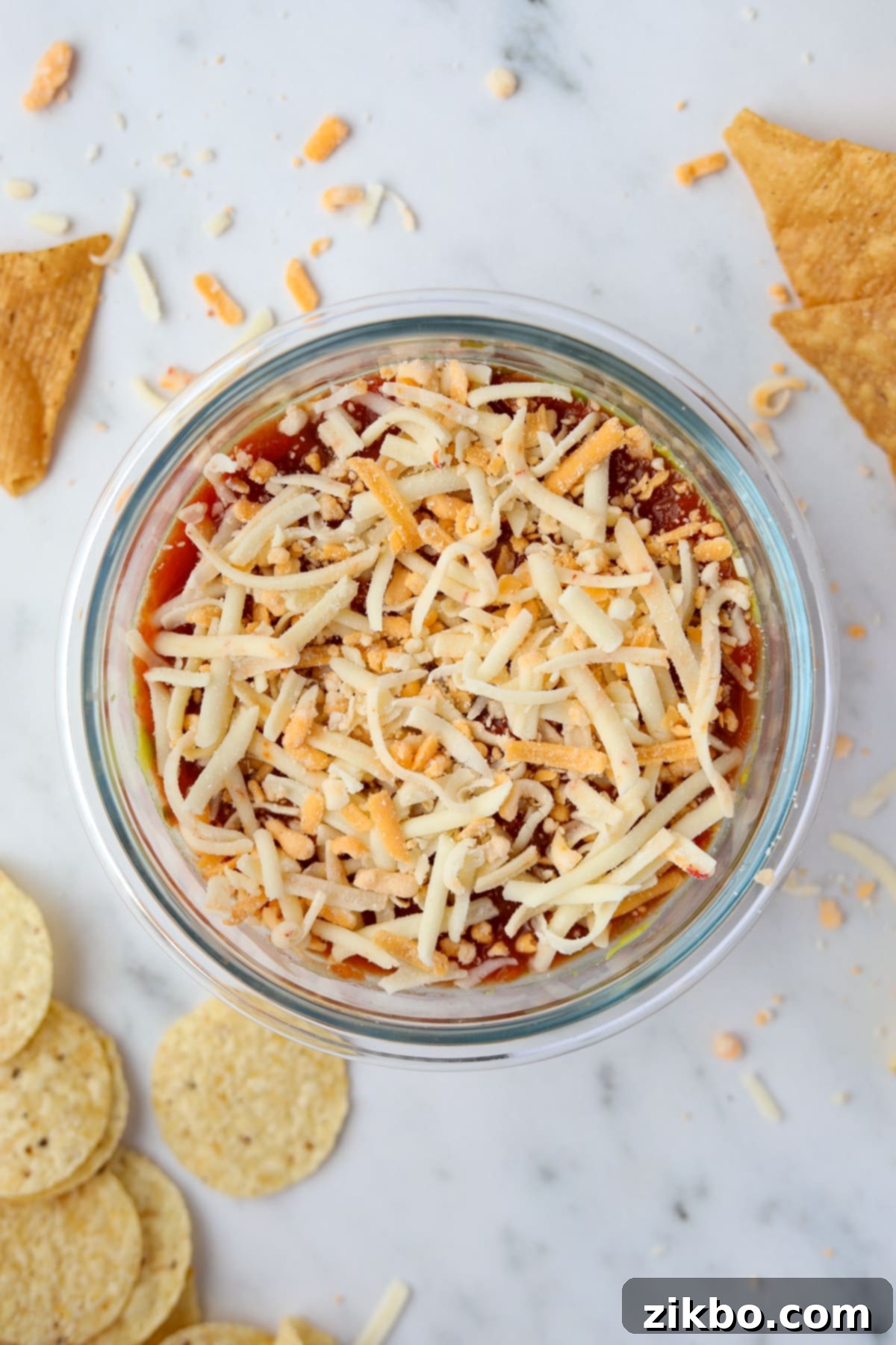 A small bowl filled with a single serving dip featuring salsa and shredded cheese.