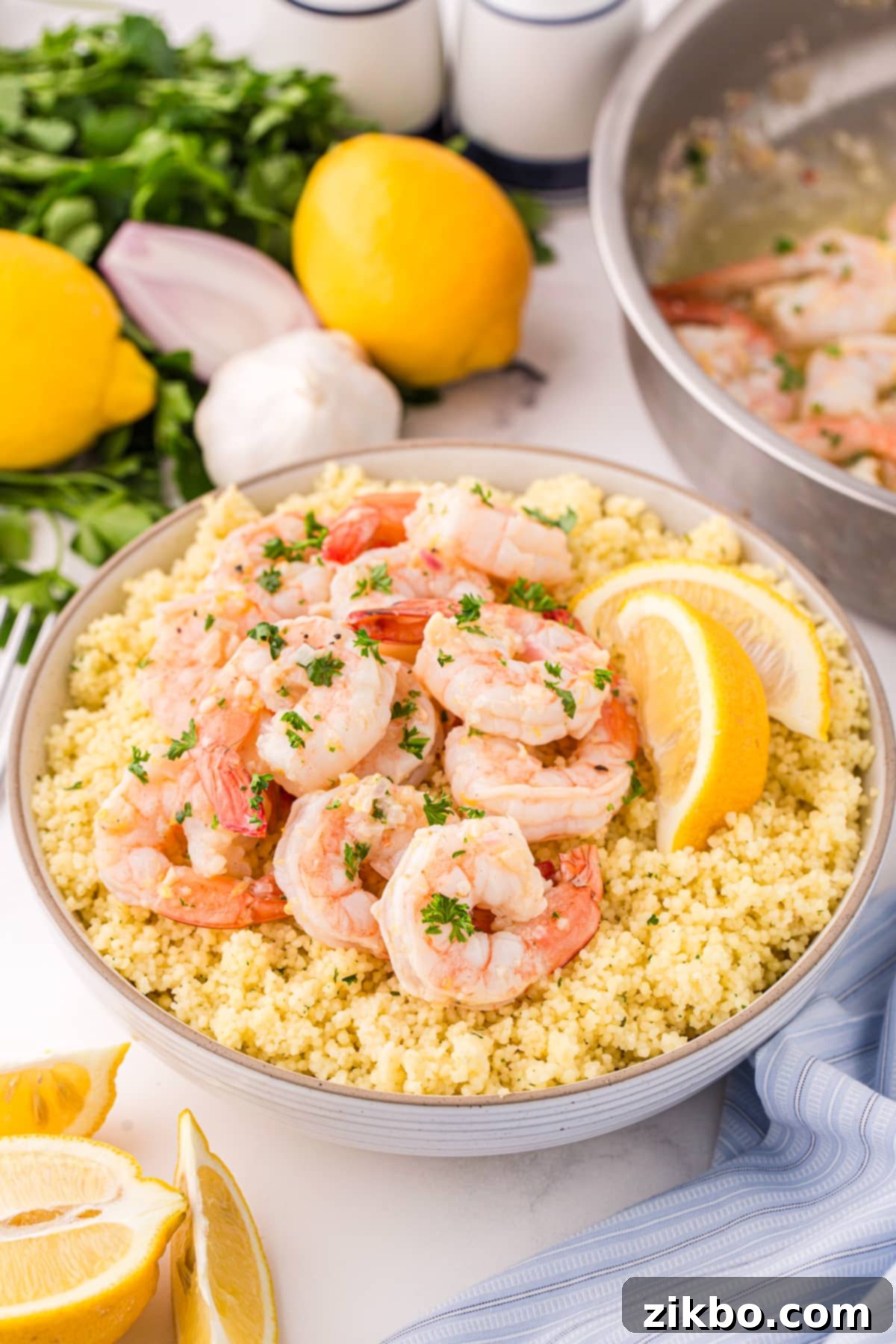 Perfectly cooked lemon garlic butter shrimp served atop a bowl of quinoa, garnished with fresh lemon wedges and parsley.