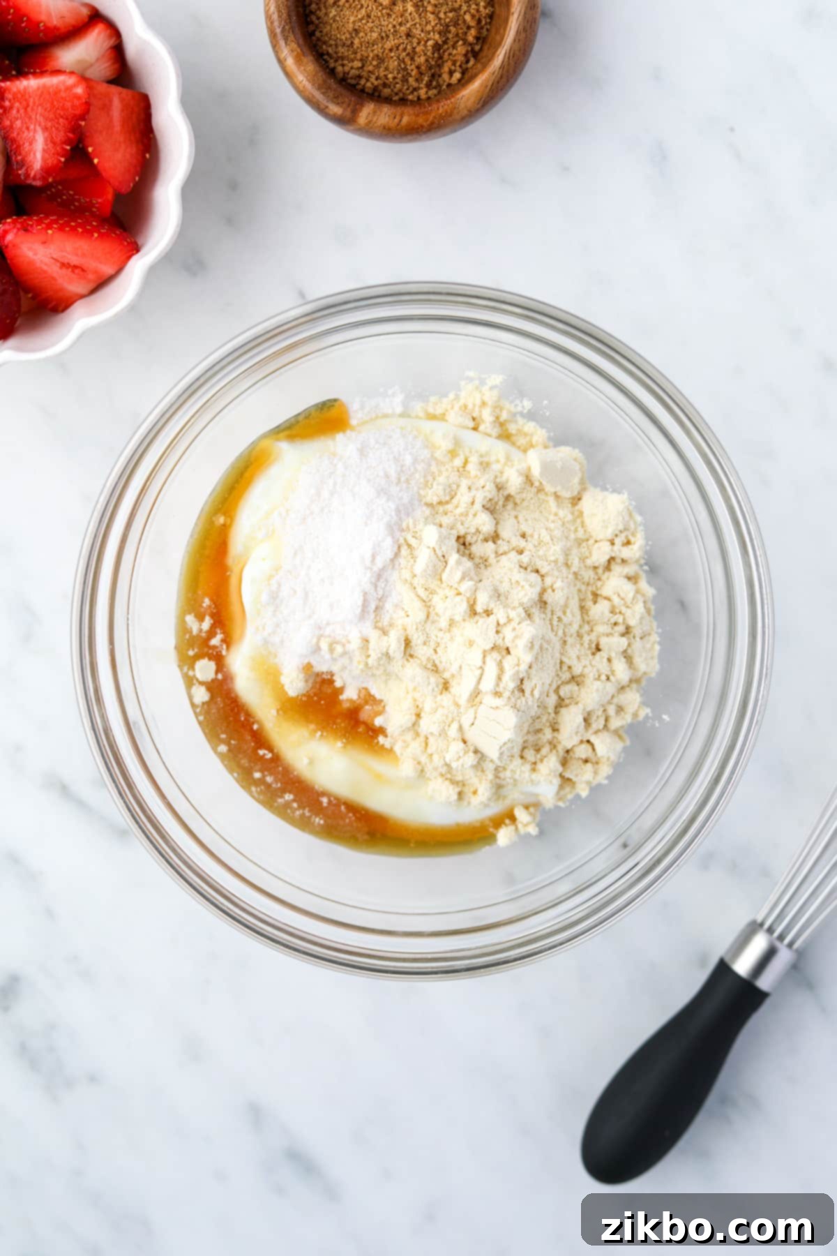 A bowl with yogurt, protein powder, maple syrup, pudding mix, and vanilla inside.