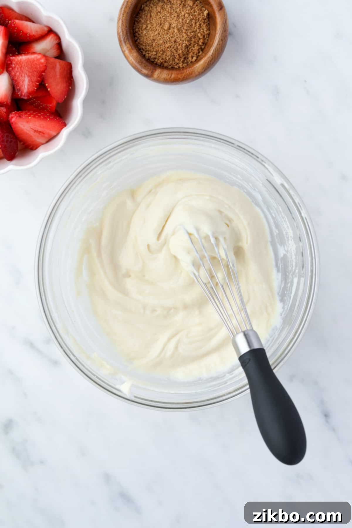 A bowl with creamy yogurt and a mini whisk.