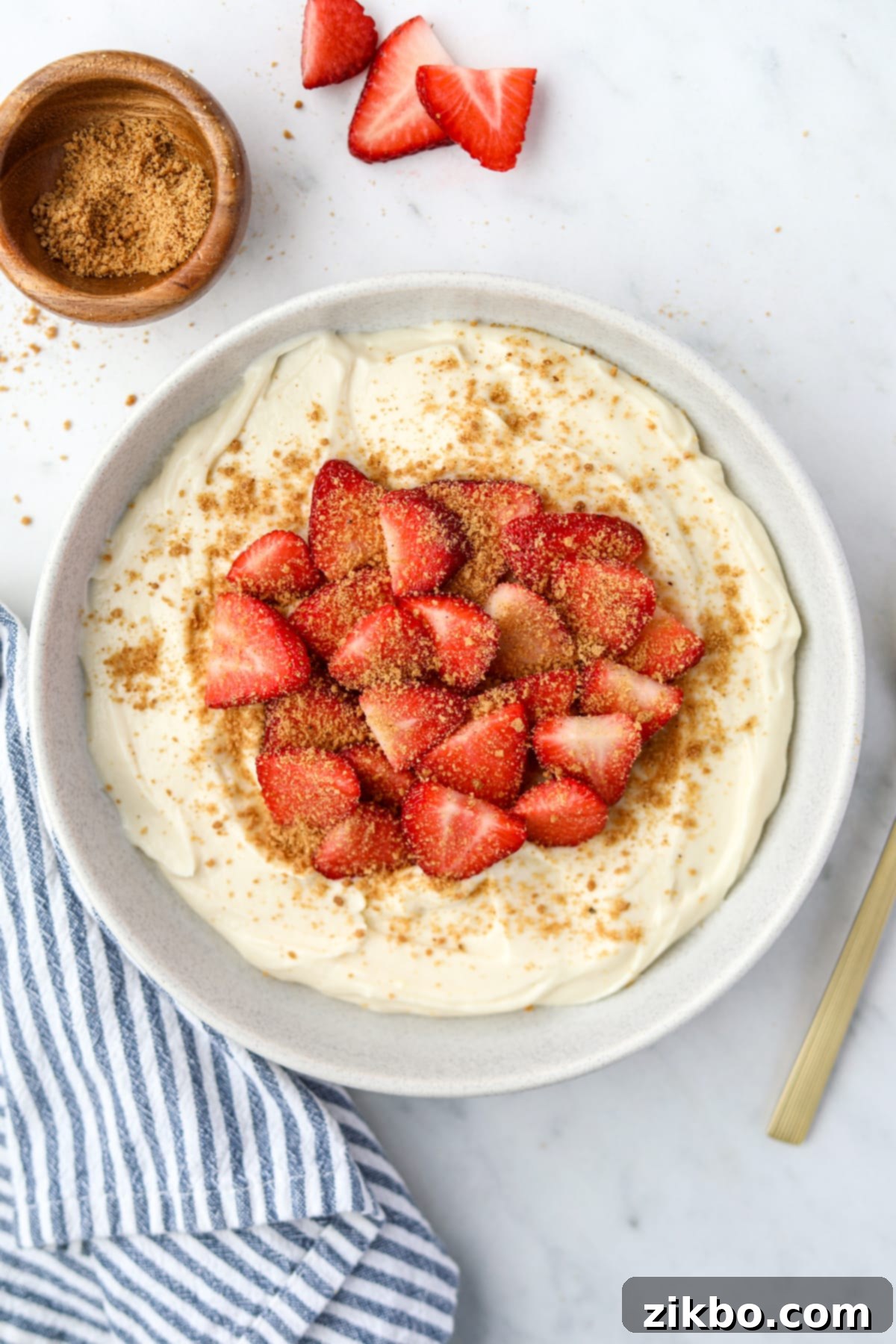 A bowl of yogurt topped with strawberries and graham cracker crumbs.
