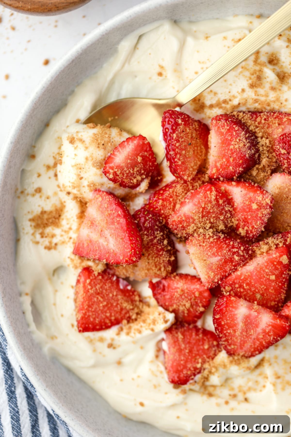A spoon scooping creamy yogurt from a bowl topped with fresh sliced strawberries.