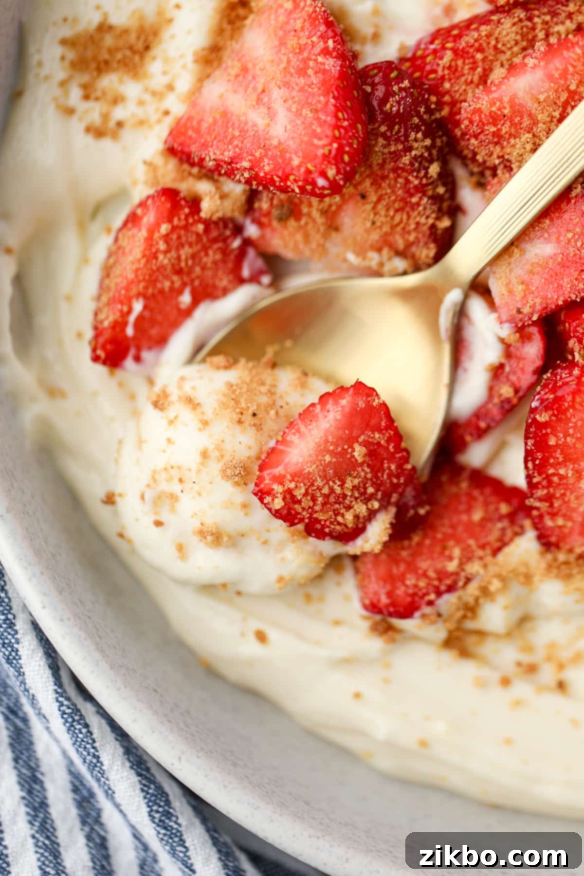 A close up of a spoon scooping yogurt from a bowl with fresh strawberries.