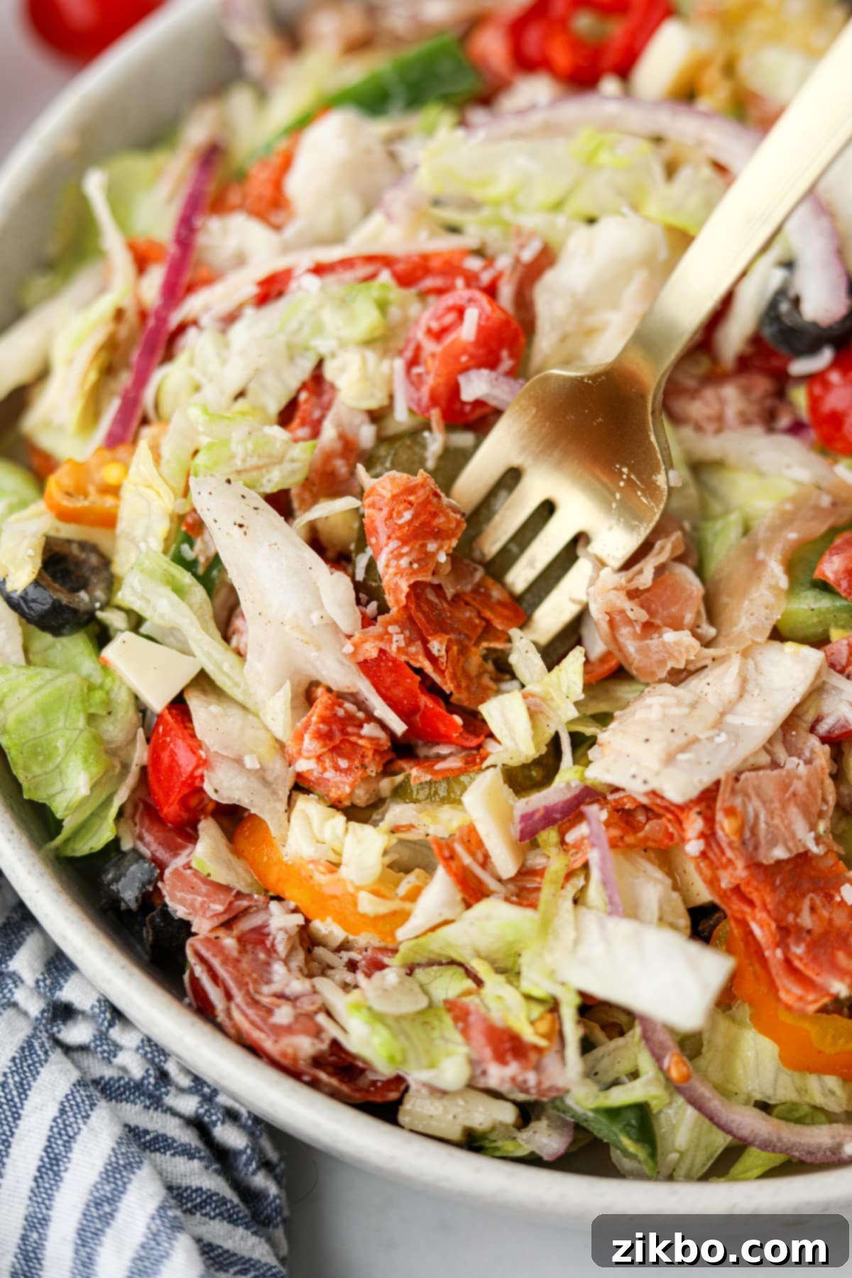 A fork lifts a generous portion of the colorful and delicious Italian Sub Salad from a bowl, ready to be eaten.