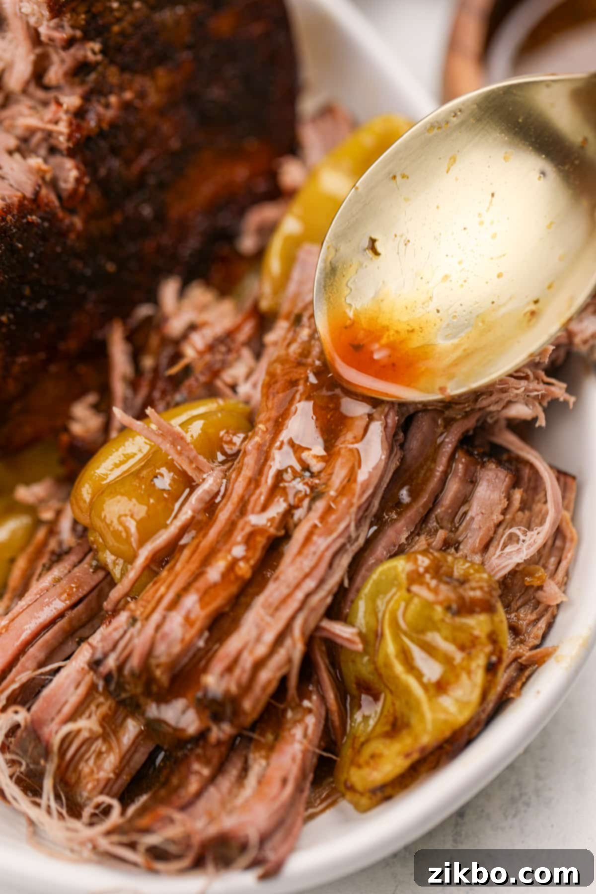 Spooning reserved juices over shredded pot roast.
