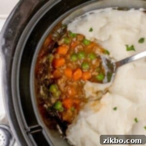 A slow cooker filled with shepherd's pie topped with mashed potatoes, ready to be served as a hearty family meal.