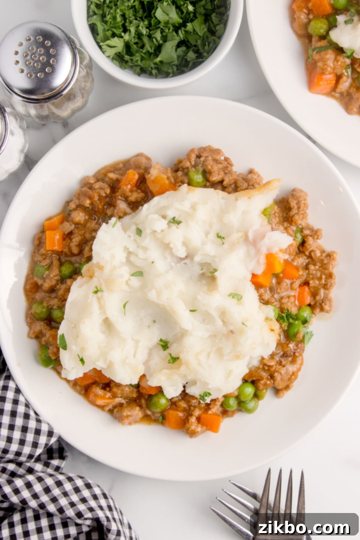 A serving of shepherd's pie on a white plate, showcasing the mashed potato topping and savory beef filling.