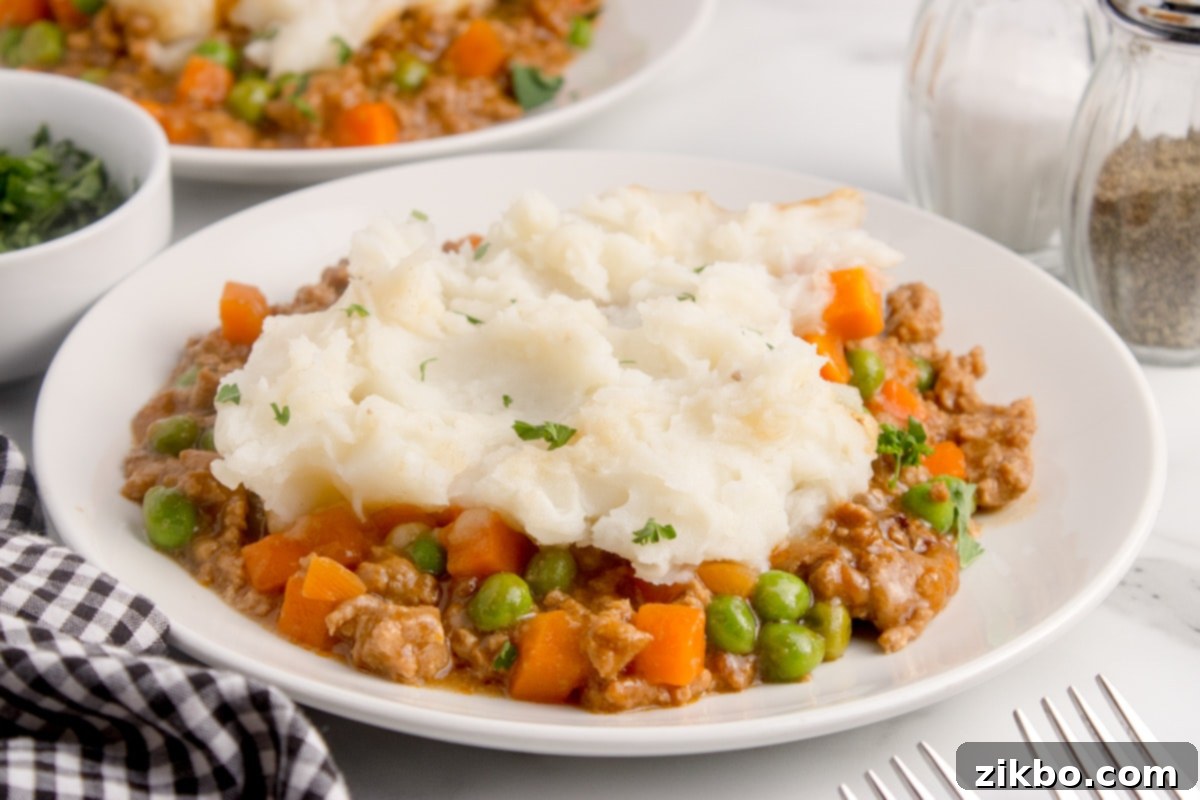 A close-up shot of a plate of slow cooker shepherd's pie, highlighting the fluffy mashed potatoes on top.