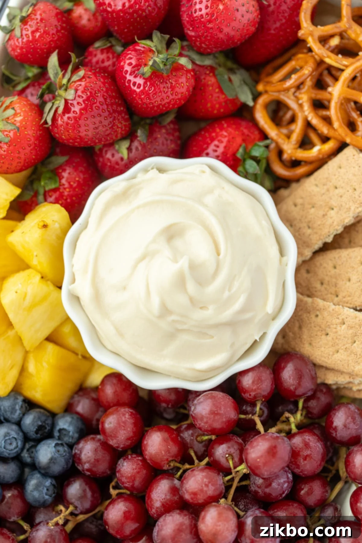 Decadent Sweet Cream Cheese Dip 6 A small bowl of cream cheese dip surrounded by fruit, graham crackers, and pretzels.