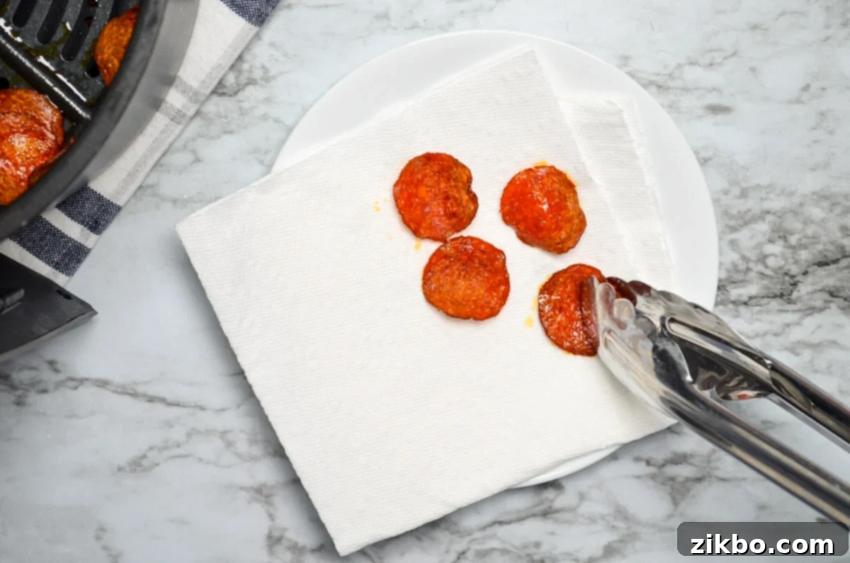Air fryer pepperoni chips being drained on a double layer of paper towels.
