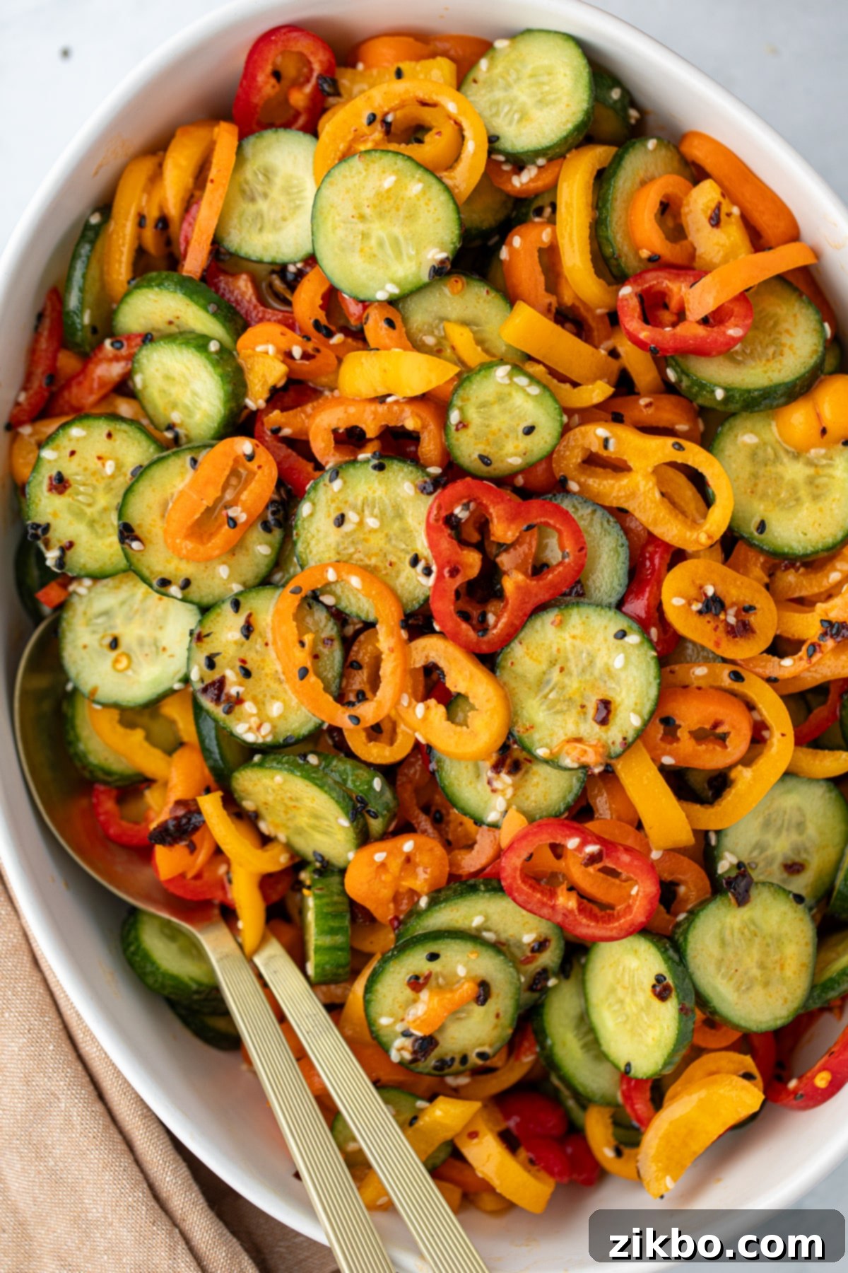 Fresh Cucumber & Bell Pepper Salad 2 A bowl filled with cucumber and mini sliced bell pepper, topped with sesame seeds.