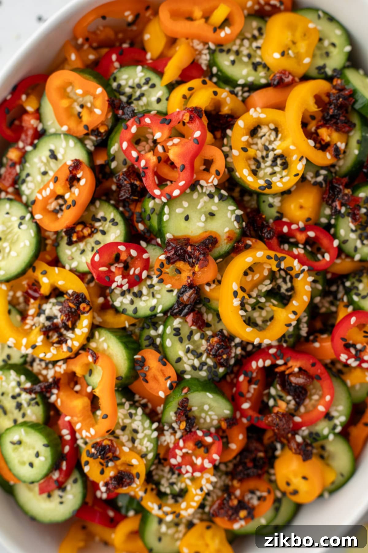 Fresh Cucumber & Bell Pepper Salad 6 A large bowl filled with cucumber and bell pepper slices, and topped with sesame seeds and chili crisp.