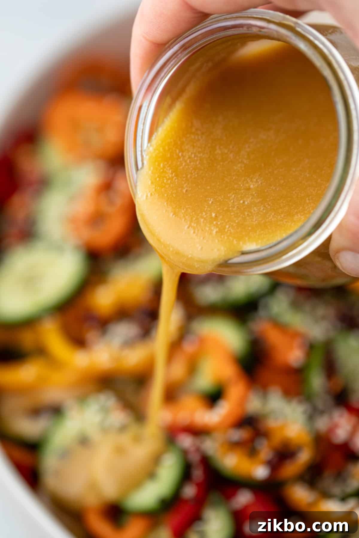 Sesame Ginger Dressing 9 The vibrant ginger sesame dressing being gracefully poured over a colorful and fresh salad, enhancing its appeal.