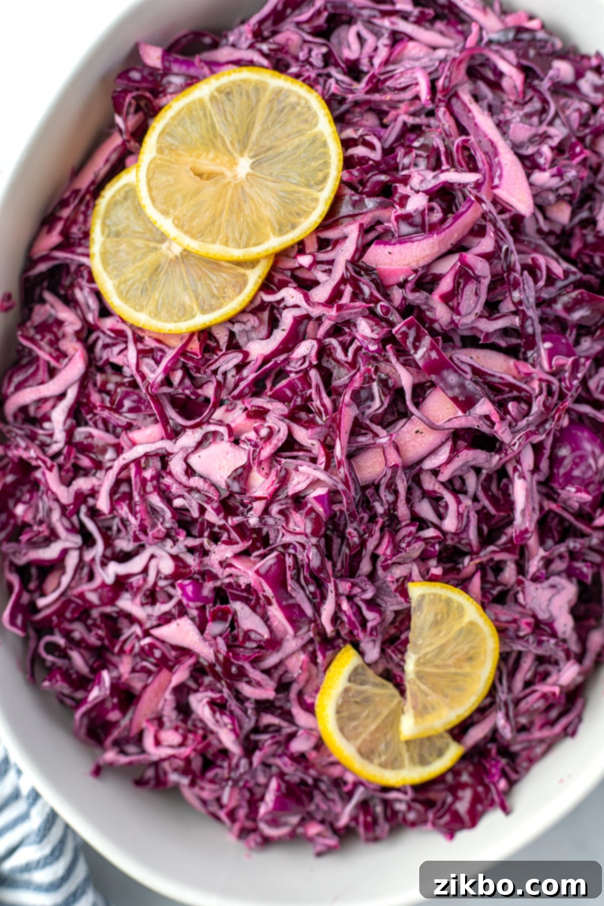 Zesty Israeli Cabbage Slaw 2 A bowl filled with red cabbage salad and garnished with lemon slices, ready to be served.