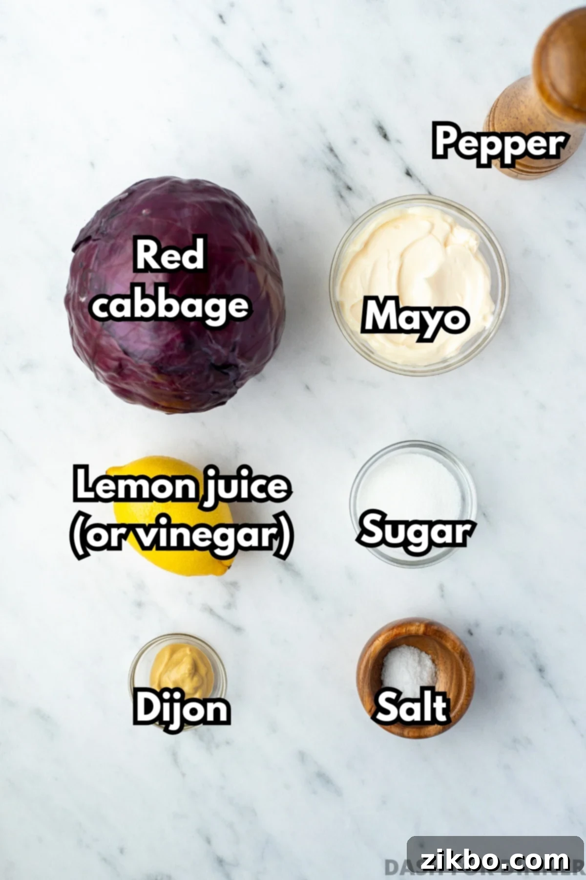 Zesty Israeli Cabbage Slaw 3 A selection of fresh ingredients including a head of red cabbage, mayonnaise, lemon, sugar, dijon mustard, and salt, laid out on a kitchen counter.