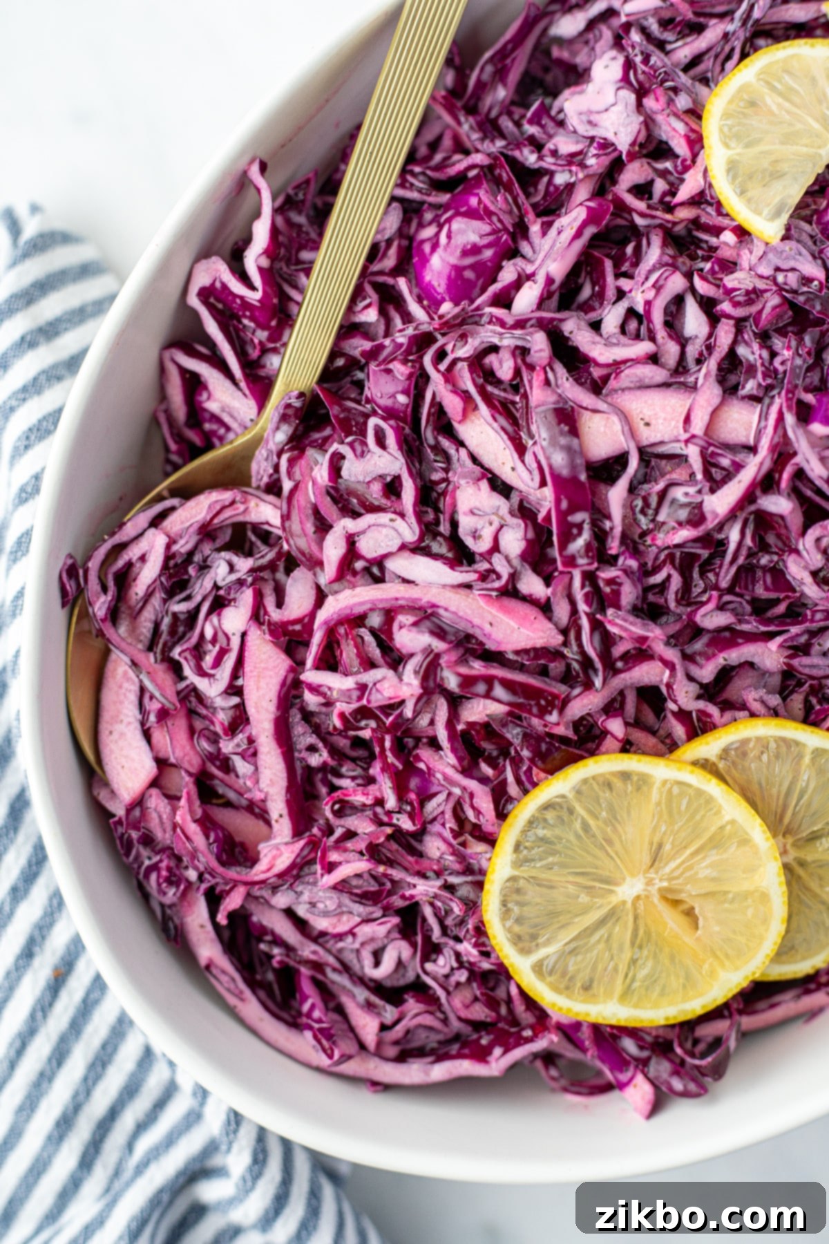 Zesty Israeli Cabbage Slaw 4 A spoon taking a portion of vibrant red cabbage salad from a large white bowl, ready to be served.