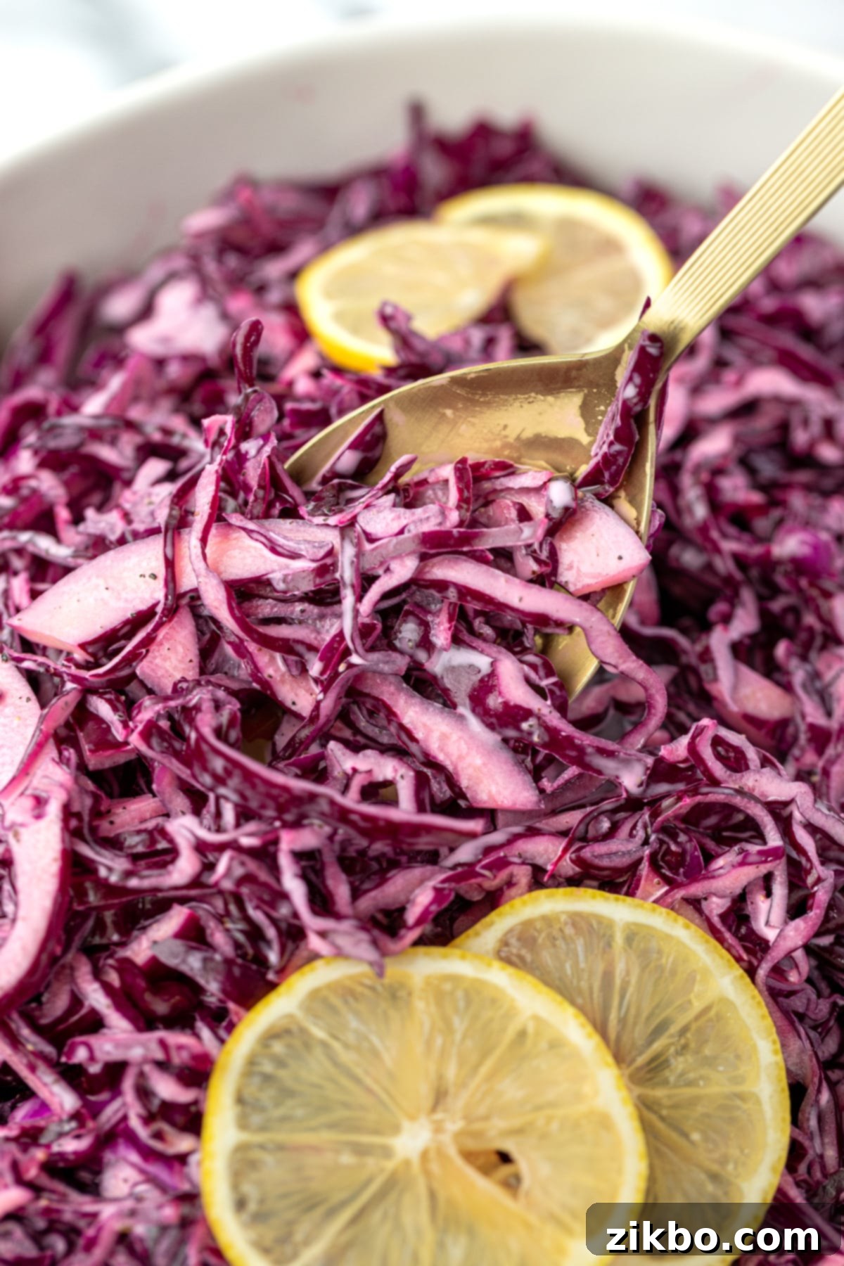 Zesty Israeli Cabbage Slaw 10 A spoon taking a portion of fresh red cabbage salad from a serving bowl, highlighting its vibrant color and crisp texture.