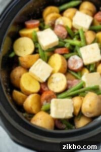 A slow cooked filled with vegetables and smoked sausage topped with butter.