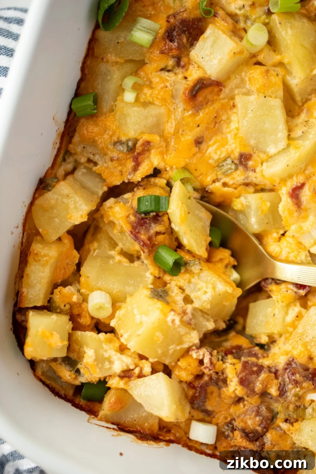 Mississippi Smothered Potatoes 2 A spoon scooping into a potato casserole with cheese and bacon.
