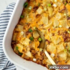 Mississippi Smothered Potatoes 9 A spoon taking a portion of potato casserole from a baking dish.