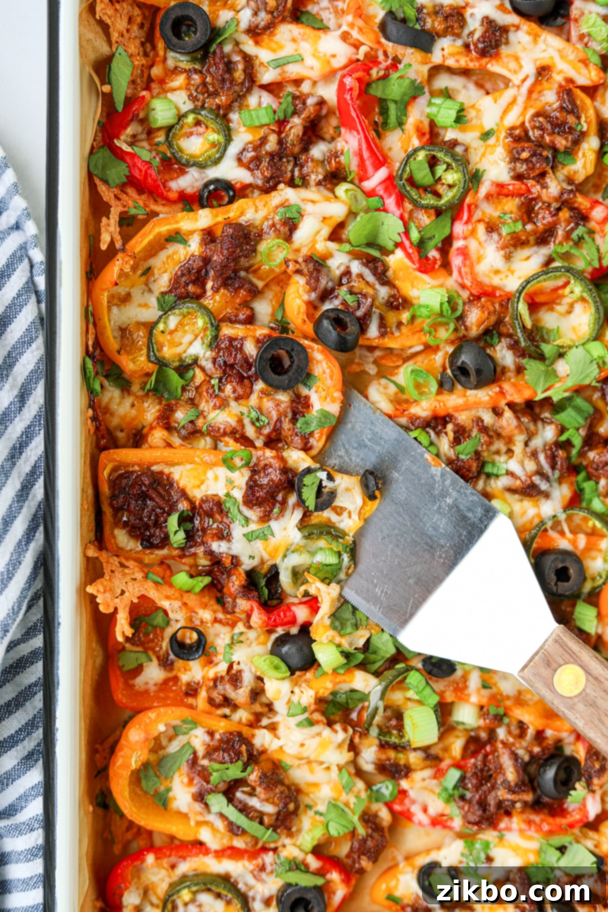 A sheet pan of bell pepper nachos with a small spatula lifting some from the pan.
