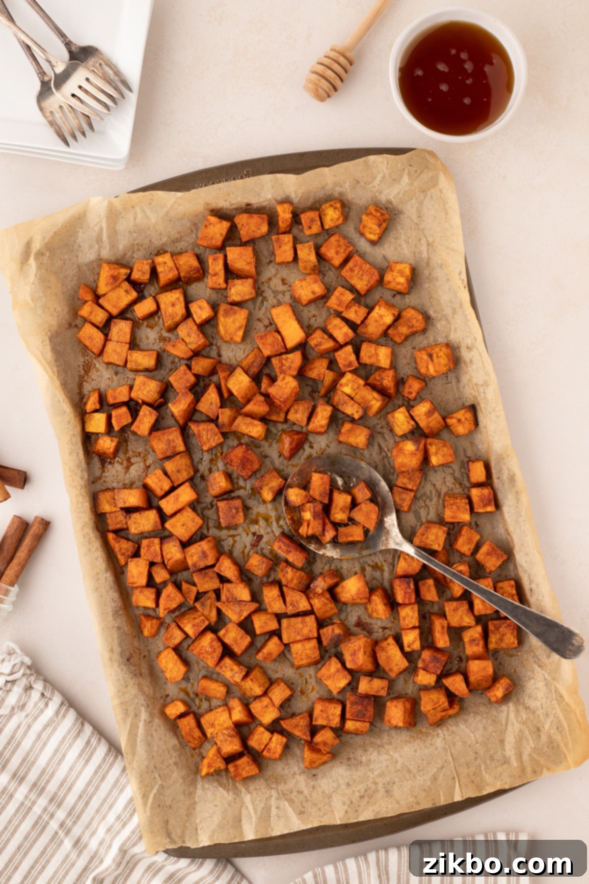 A baking sheet filled with golden-brown roasted sweet potato cubes, perfectly seasoned and ready to serve.