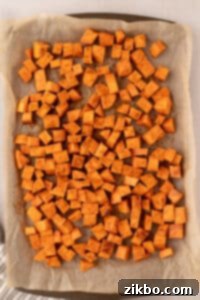 A sheet pan filled with roasted sweet potato cubes.