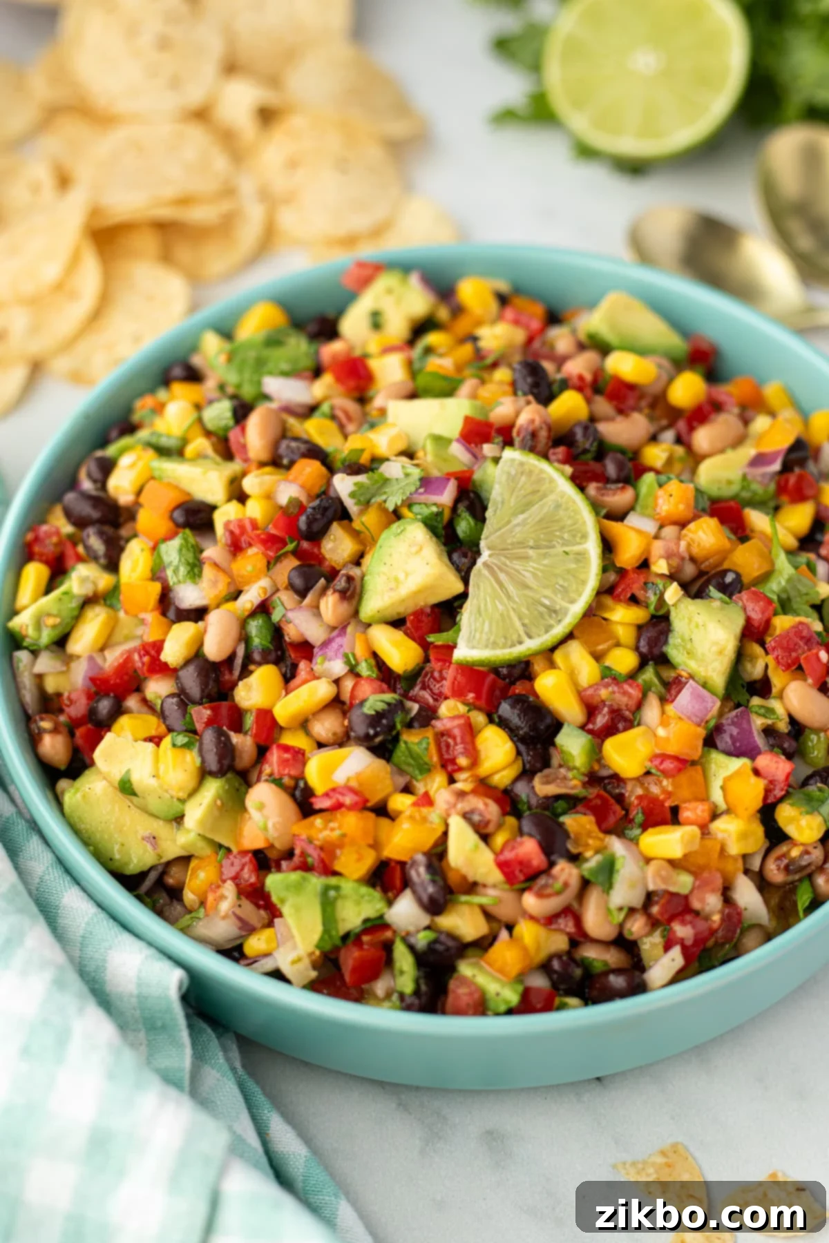 A bowl of bean salad topped with a wedge of fresh lime, ready to be served.