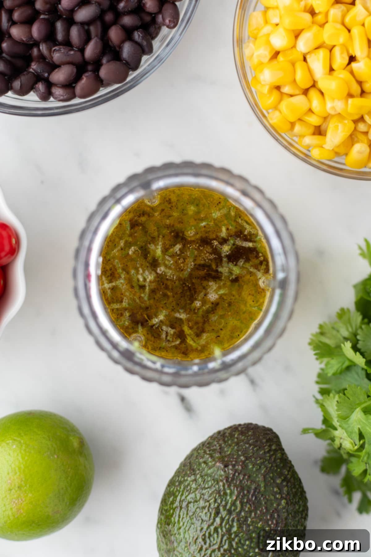 A mini blender filled with olive oil, lime juice, vinegar, and other dressing ingredients.