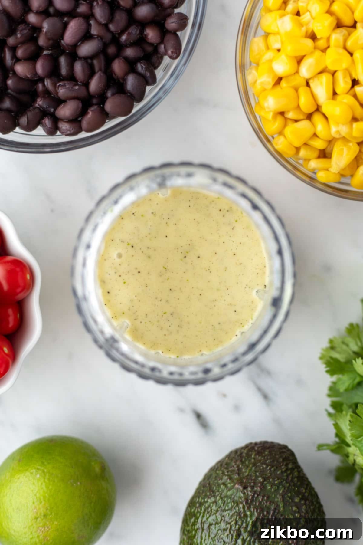 A small blender cup filled with a very light green, emulsified dressing.
