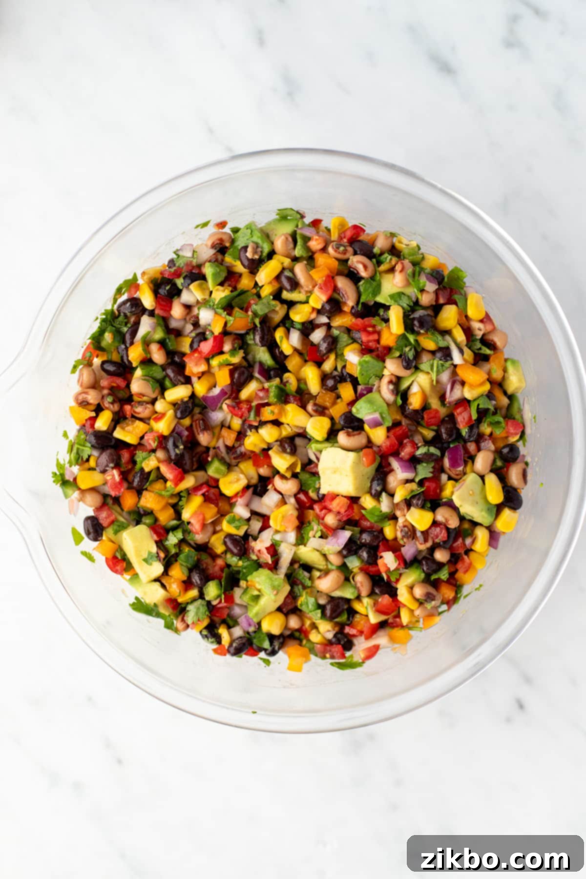 A bowl of colorful bean salad with avocado and corn, perfectly mixed.