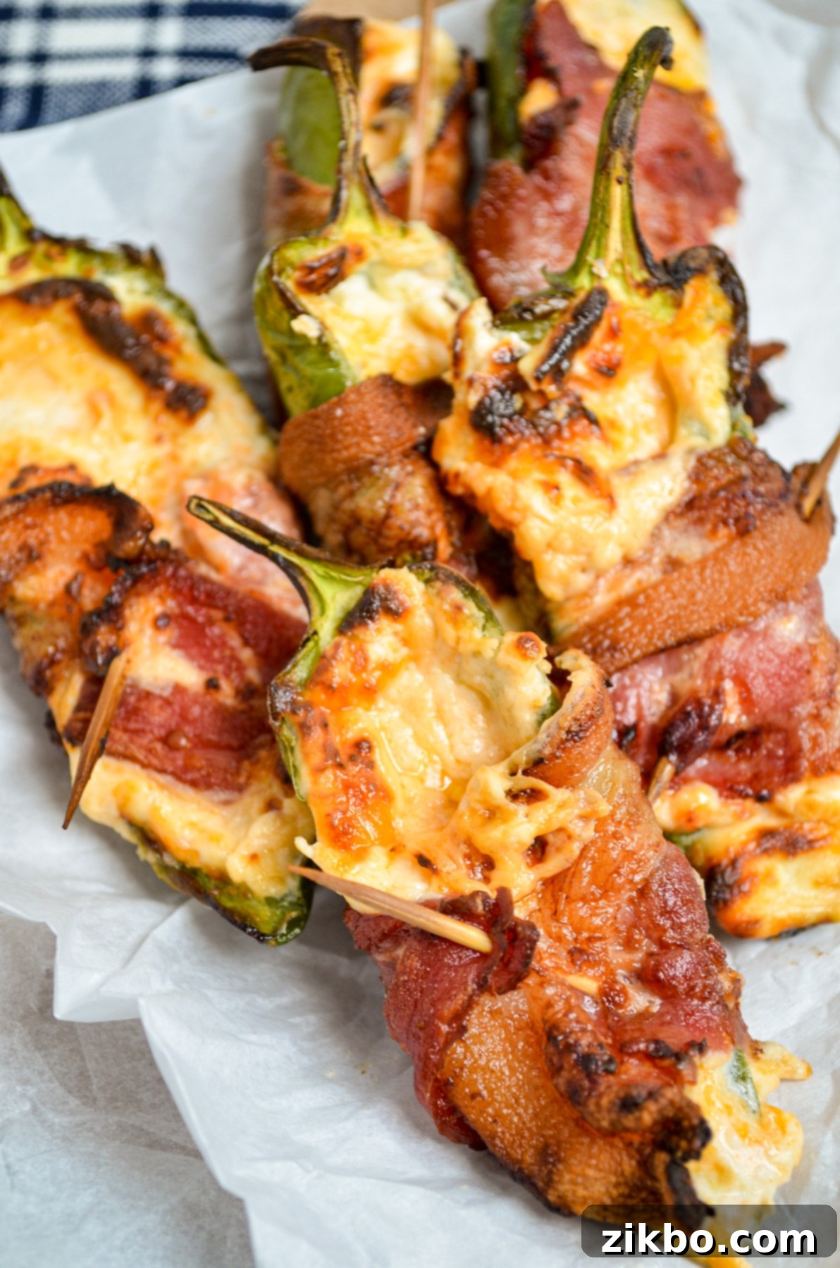 A delicious plate of bacon-wrapped jalapeno poppers, freshly cooked in an air fryer, garnished with fresh herbs, ready to be served.