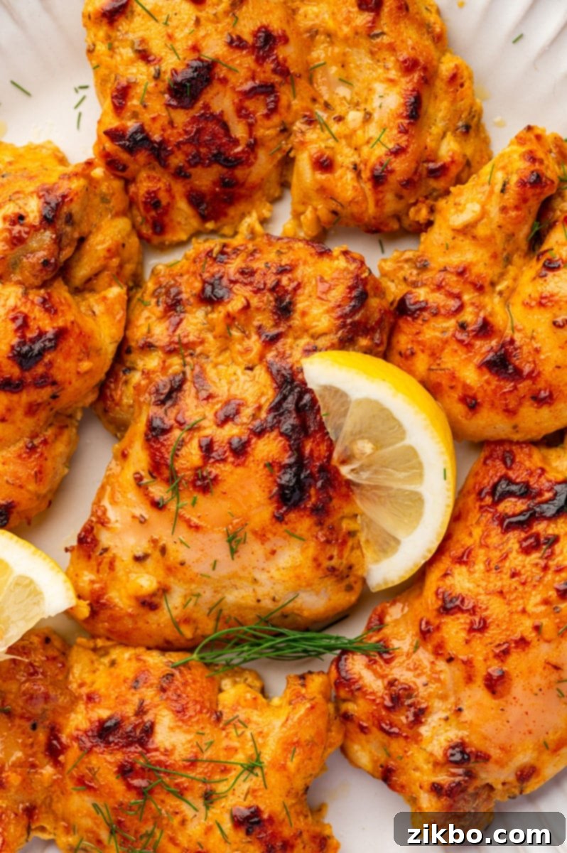 Delicious Greek Yogurt Chicken 2 Seasoned chicken thighs garnished with fresh dill and lemon.