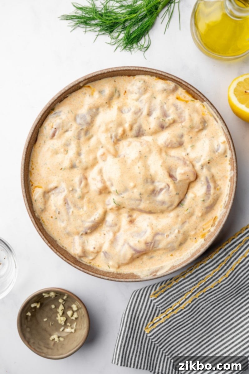 Delicious Greek Yogurt Chicken 5 A bowl filled with yogurt marinade and chicken pieces.