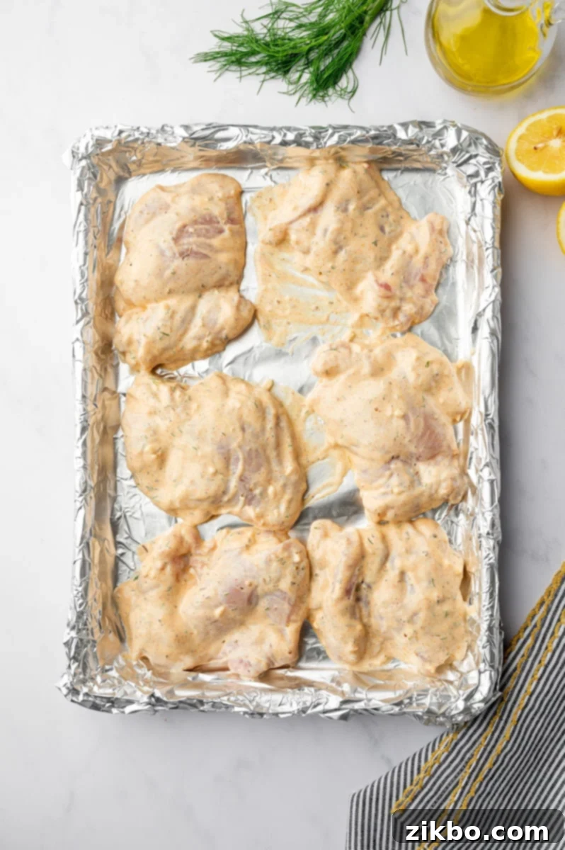 Delicious Greek Yogurt Chicken 6 Yogurt marinated chicken thighs on a aluminum foil lined baking sheet.
