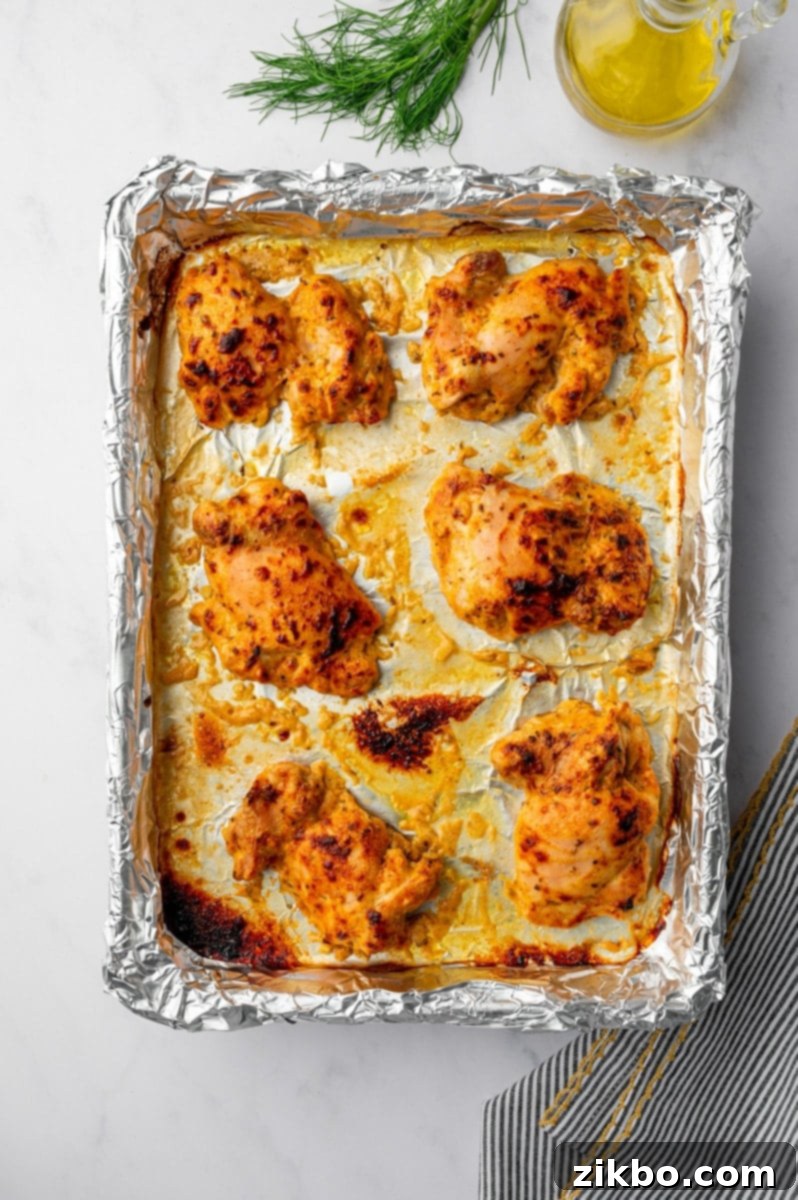 Delicious Greek Yogurt Chicken 7 Cooked chicken thighs on a foil-lined baking sheet.