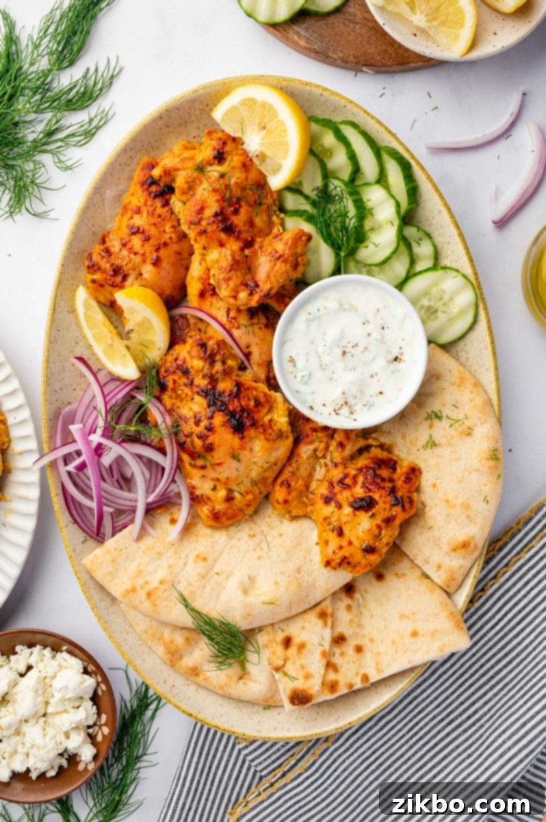 Delicious Greek Yogurt Chicken 10 A platted filled with seasoned chicken thighs, cucumber, red onion, and pita.