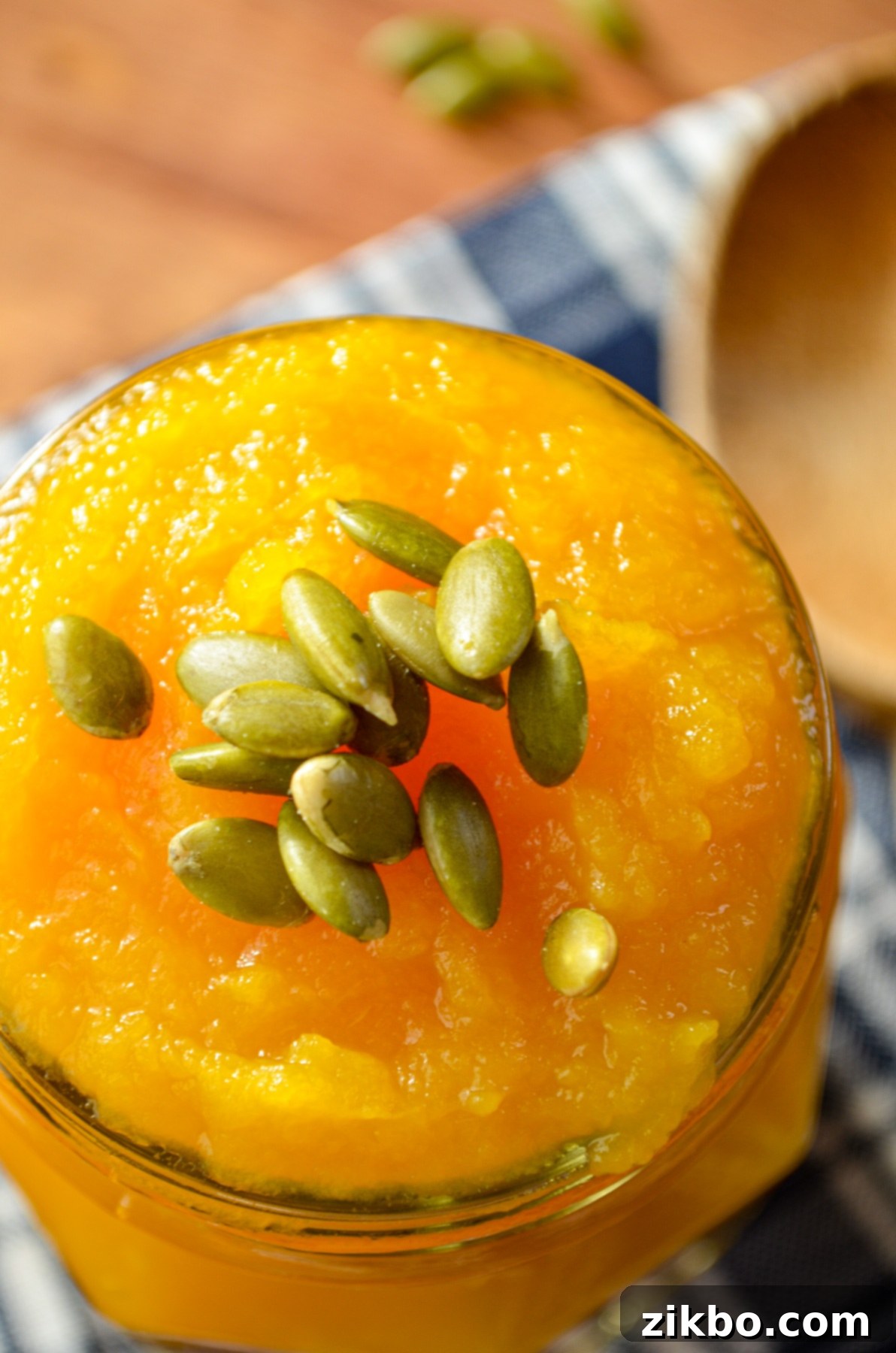 A glass jar of homemade pumpkin puree, garnished with pepitas.